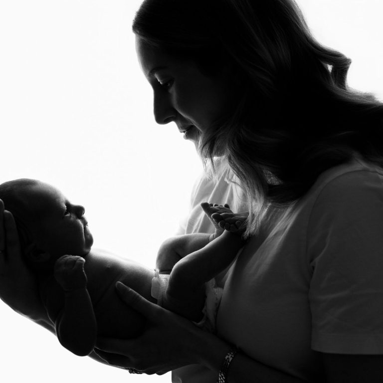 A mother gently holds her baby in a loving silhouette.